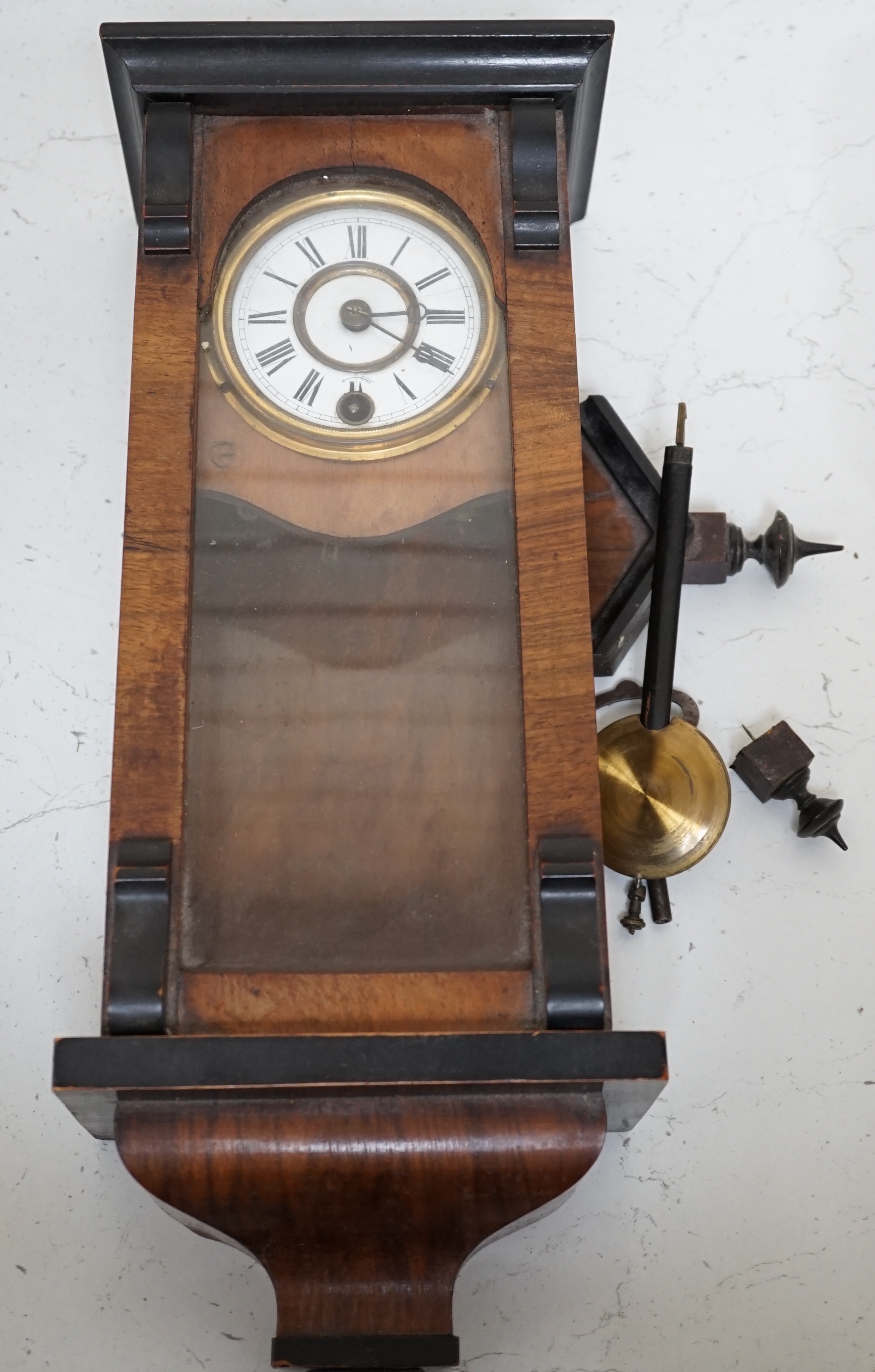 A small walnut cased wall clock with enamel dial with pendulum and key. Condition - poor